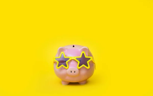 A pink piggy bank in fun glasses at a party. Yellow background. — Stok fotoğraf