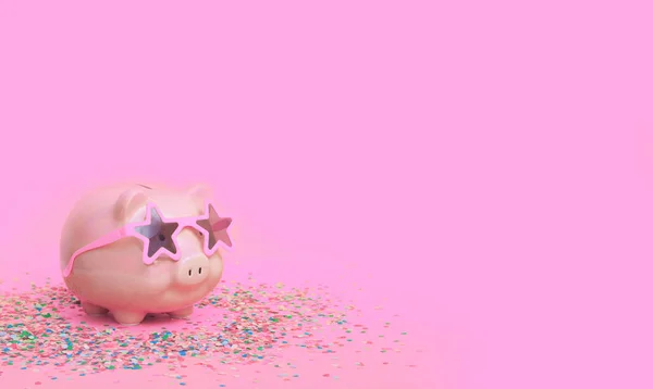 A pink piggy bank in fun glasses at a party. Pink background. — Stok fotoğraf