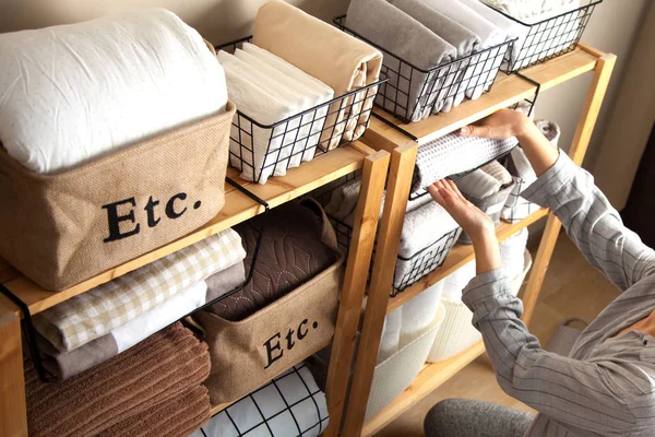 A woman is doing spring cleaning. Folds bedding, blankets, towel