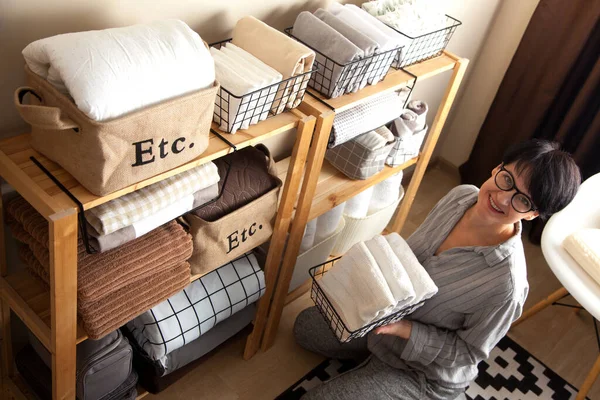 Una mujer está haciendo limpieza de primavera. Plegables ropa de cama, mantas, toalla — Foto de Stock