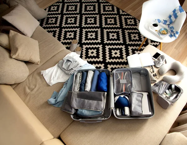 Open grey suitcase with different clothes packed for journey at — Stock Photo, Image