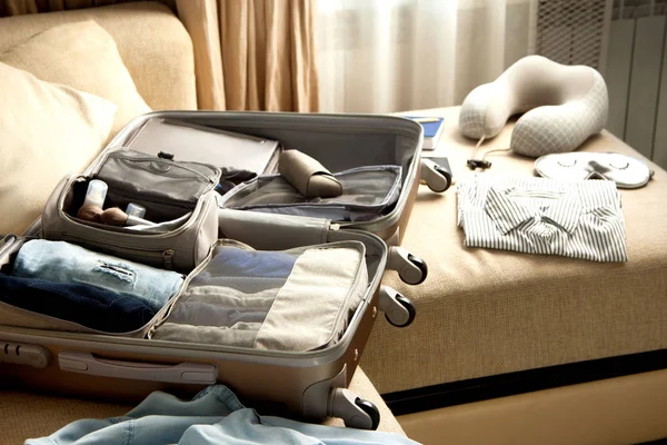 Otevřít šedý kufr s různými šaty zabalené na cestu na — Stock fotografie