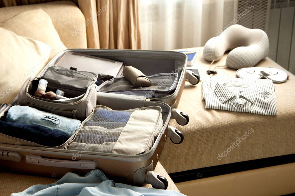 Open grey suitcase with different clothes packed for journey at 