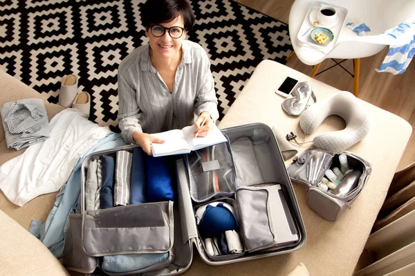 Maleta de color gris abierto con diferentes prendas de vestir embaladas para el viaje en — Foto de Stock