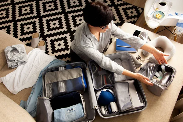 Valise ouverte grise avec différents vêtements emballés pour le voyage à — Photo