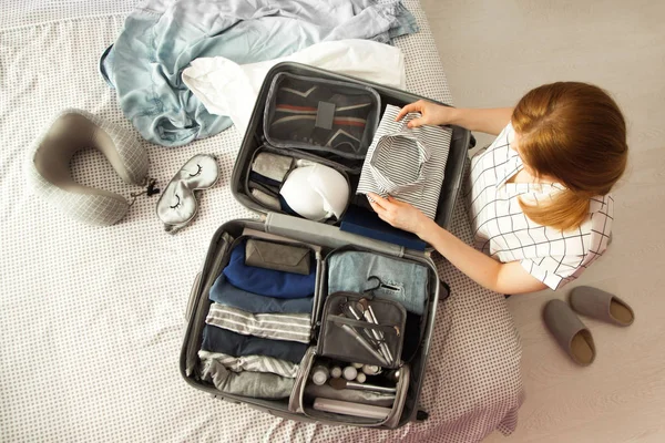 女性手在床上抱着旅行箱 特写镜头 海滩配件在打开的行李箱 旅行的车轮袋 不同的衣服 — 图库照片