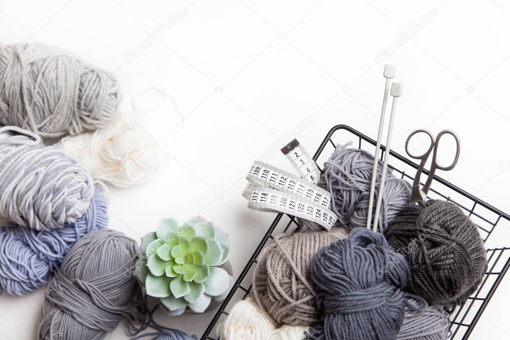 Yarn for knitting neutral colors. Accessories for knitting. Centimeter tape, scissors, knitting needles. Started knitted fabric.