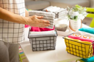 Spring cleaning of closet. Vertical tidying up storage. Neatly folded bright color clothes in the metal black baskets for wardrobe. 