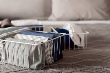 Bir kadın elbiselerini katlayıp metal beyaz sepetlere ve kutulara koyar. Kuzey tarzı minimalizm.