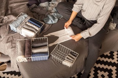 Gardıropta sipariş verin. Kıyafetler düzgünce katlanmış. Gri arka plan. Yatak odası, düzenleme, dağınıklık.