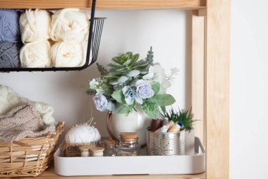 Farklı dikiş malzemeleri ve iplikler sepetlerde yatar ve beyaz bir arka planda dikiş makinesi olan ahşap bir rafta dururlar. Terzi ve nakış işyeri kavramı. Kopyalama alanı