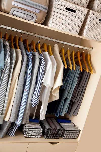 Wardrobe with perfect order clothes in blue and light shades on the hangers and things in containers. The concept of organizers and cleanliness in the house