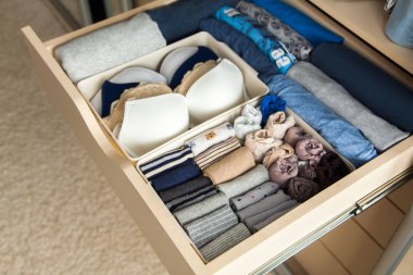 Gri mavi renkli ve aksesuarlı düzgünce katlanmış şeylerin üst görüntüsü dolaptaki çekmecede. Kıyafetlerin mükemmel bir şekilde düzenli ve uygun bir şekilde depolanması.