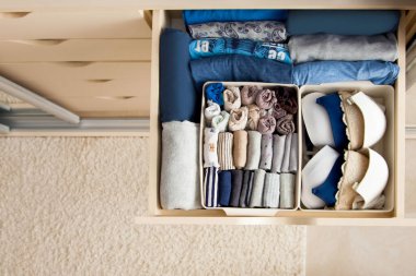 Kadın eşyalarının ve mavi renkli aksesuarların en üst görüntüsü bayan sinek sistemi tarafından düzenlenirken gardırop dolabının çekmecesindedir. Uygun ve akıllı depolama konsepti