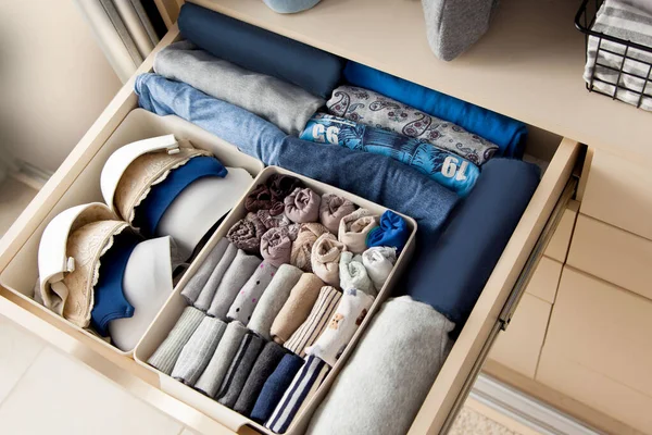 Top view of womens things and accessories of blue color are in the drawer of the wardrobe closet during tidying by the lady fly system. Convenient and intelligent storage concept
