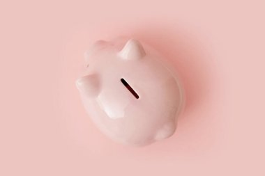 Pembe arka planda duran domuz kumbarasının üst görüntüsünü kapatın. İşsizlik ve kriz zamanları için para tasarrufu kavramı. Reklam için yer var. Metin için yer