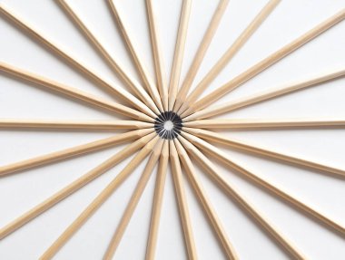 Kalemlerin simetrik olarak birbirine bağlı üst görünümü beyaz bir arkaplanda merkezdeki kalemlerin uçlarıyla. Uyum ve takım çalışması kavramı.