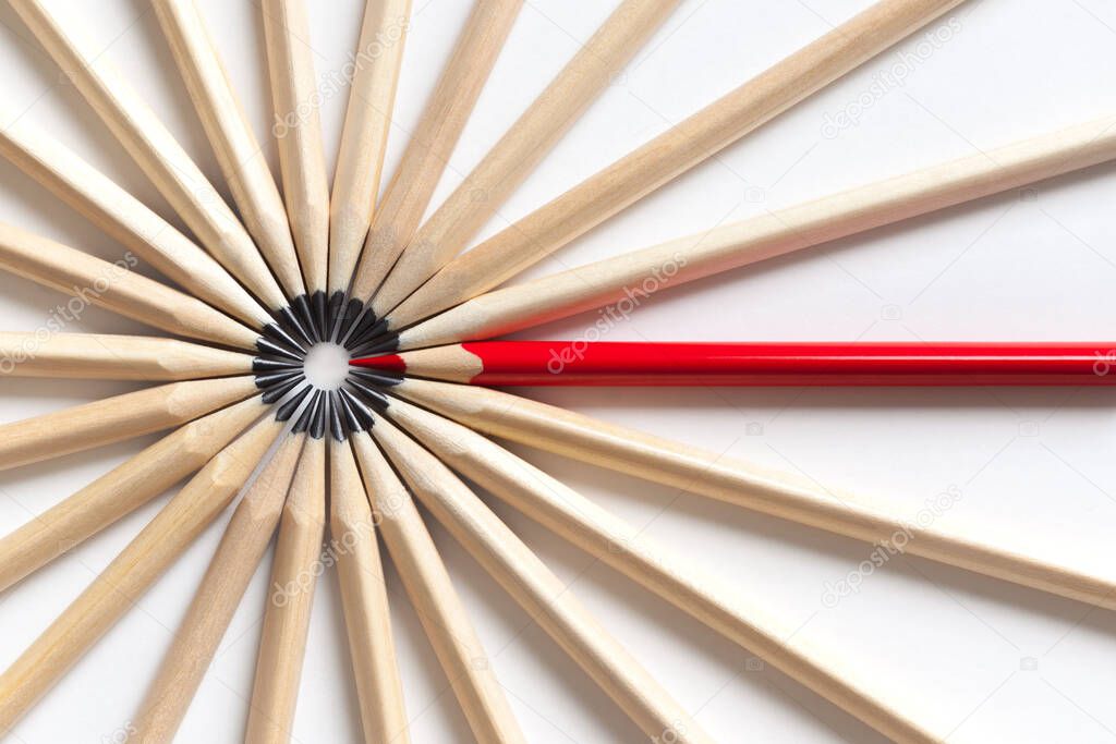 Top view of a red pencil tends to fall into a circle of gray pencils lying on a white background. Concept of unsuitable standout employee in an office team. Eccentric concept