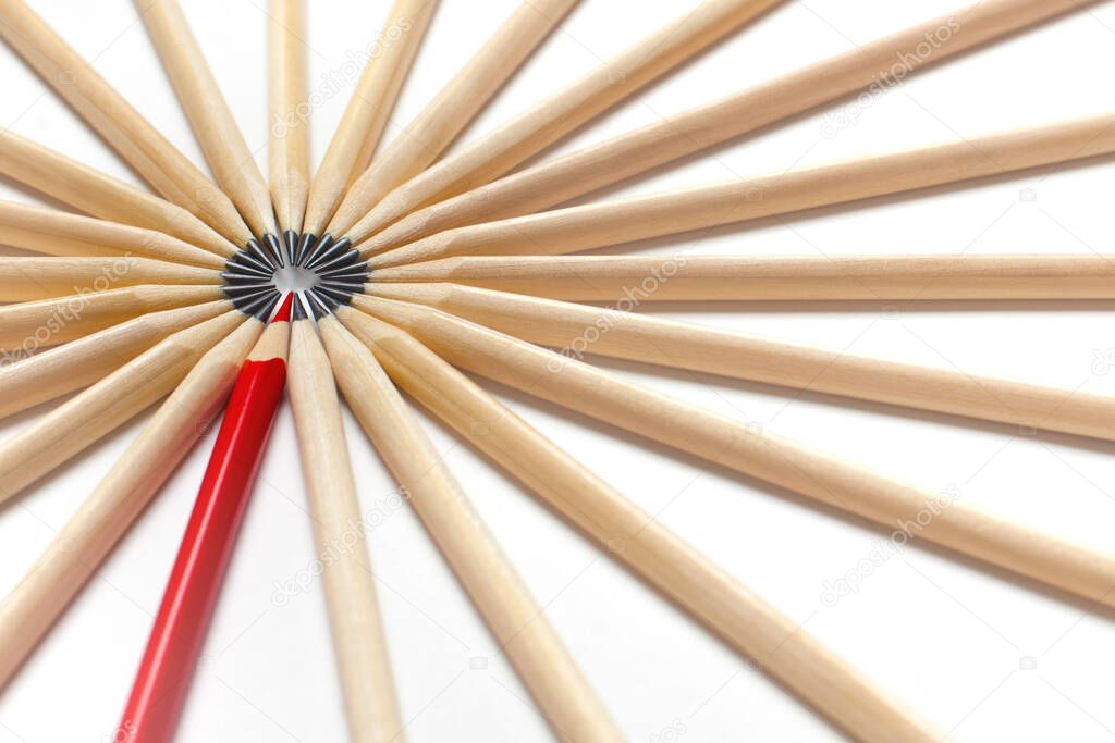 Top view of a red pencil tends to fall into a circle of gray pencils lying on a white background. Concept of unsuitable standout employee in an office team. Eccentric concept