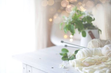 Çiçek açan elma ağacının güzel dalları pencerenin yakınındaki bir masada beyaz bir vazoda. Beyaz koltuk ve ekose.