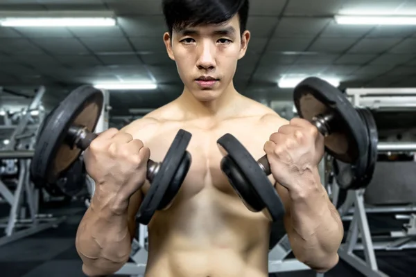 Homem de fitness em treinamento, mostrando exercícios com halteres no ginásio — Fotografia de Stock