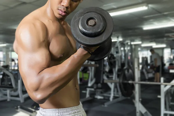 Homem de fitness em treinamento, mostrando exercícios com halteres no ginásio — Fotografia de Stock