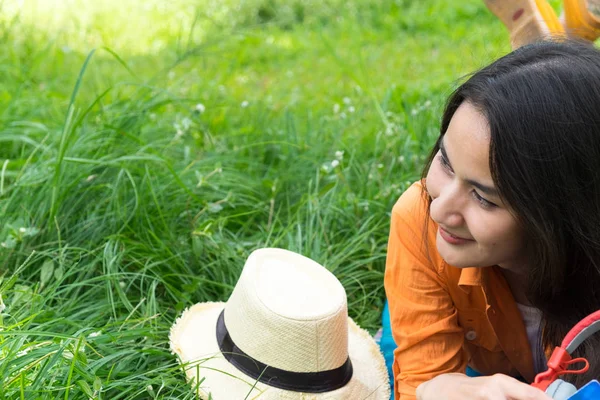 Junge Frau liegt auf grünem Gras und genießt die Musik mit Kopfhörern — Stockfoto