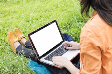 Yeşil çimenlerin üzerinde genç kadın oturup zevk müzik ile laptop Outdo