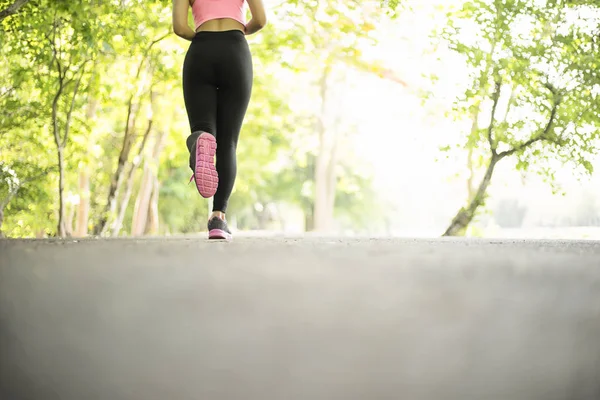 Молода спортивна жінка біжить по дорозі в саду, спорті і вітальні — стокове фото