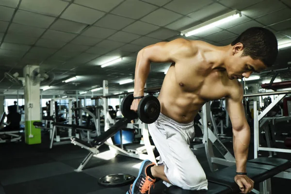 Homem de fitness em treinamento, mostrando exercícios com halteres no ginásio — Fotografia de Stock