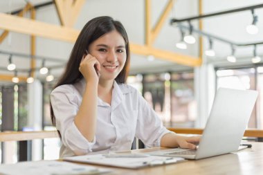 Kafedeki iş kadını cep telefonuyla biriyle konuşuyor.