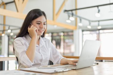 Kafedeki iş kadını cep telefonuyla biriyle konuşuyor.