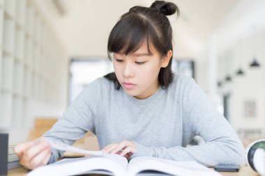 Bayan üniversite öğrencisi kütüphane, eğitim ve öğrenim konseptinde kitap okuyor