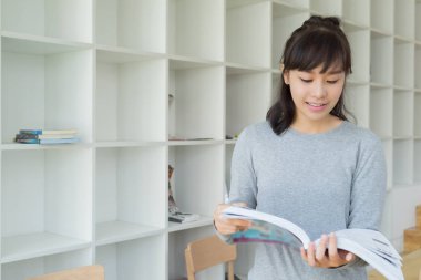 Bayan üniversite öğrencisi kütüphane, eğitim ve öğrenim konseptinde kitap okuyor