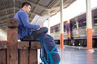 Sırt çantalı gezgin tren istasyonundaki haritayı kullanarak konumu arıyor, seyahat kavramı