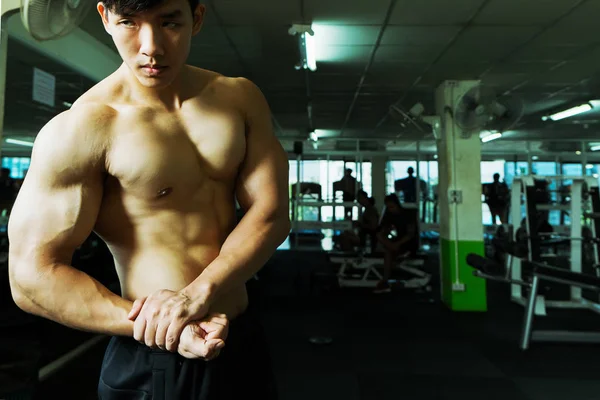 Hombre musculoso posando en el gimnasio con una toalla sobre los hombros.  concepto de fitness.