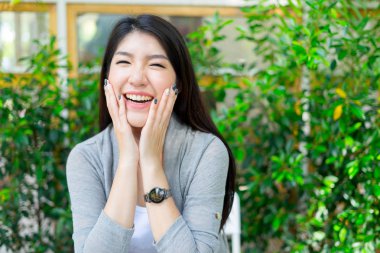 Kafede oturmuş kameraya bakan mutlu bir kadın.