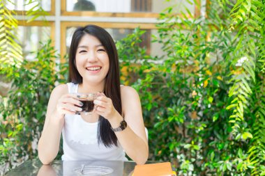 Kafede oturmuş kameraya bakan mutlu bir kadın.