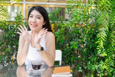 Kafede oturmuş kameraya bakan mutlu bir kadın.