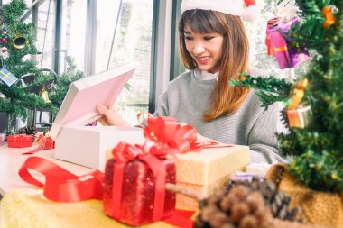 Noel Baba şapkası takan mutlu bir kadın Noel hediyesini açıyor, Noel konsepti
