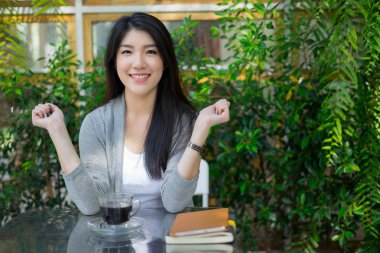 Kafede oturmuş kameraya bakan mutlu bir kadın.