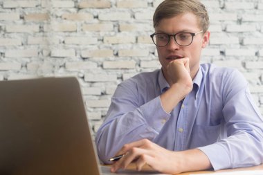 Mobil dizüstü bilgisayarla çalışan genç iş adamı ve belge ofisi, iş konsepti