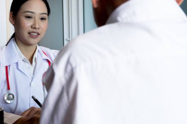 Beyaz üniformalı doktor önlüğüyle görüşmeyi kapatın ve hastaya danışmanlık yaparken başvuru formunu doldurun, tıbbi konsept