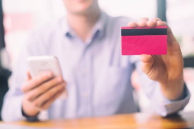 Adamın elinde kredi kartı var ve laptop ve akıllı telefon alışveriş sitesi kullanıyor, alışveriş kavramı