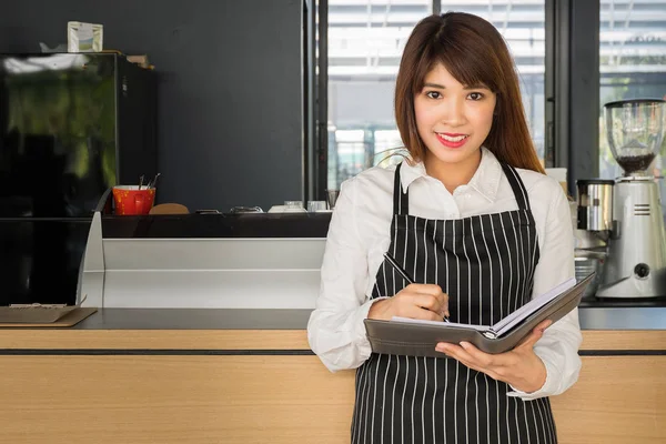 female business owner taking notes in notebook in coffee shop