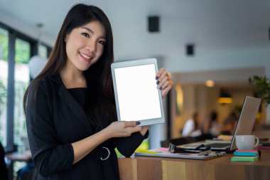 İşletme sahibi elinde tablet bilgisayarla kahve dükkanının önünde gülümseyerek duruyor.