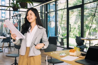 Ofis penceresinin yanında belgeyle duran genç iş kadını, iş konsepti