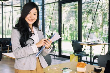 Ofis penceresinin yanında belgeyle duran genç iş kadını, iş konsepti