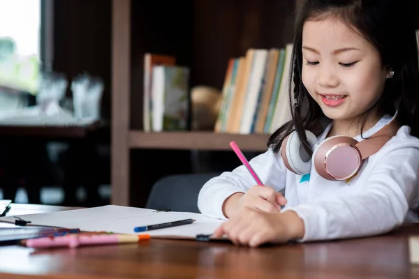 かわいい女の子は笑顔で座って図書館に本を書く子供の概念教育の概念 — ストック写真