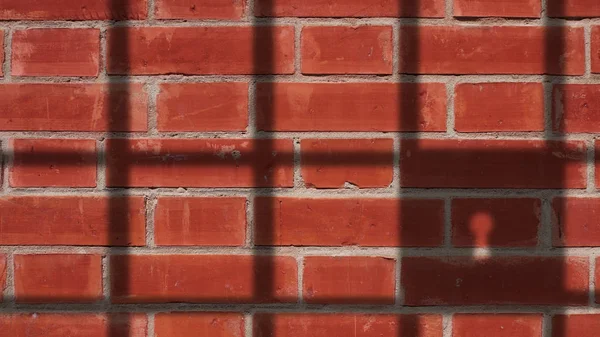 Sombra de la cárcel en la pared de ladrillos rojos . —  Fotos de Stock